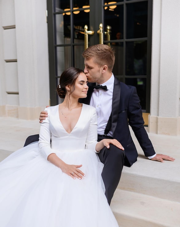 Bride and groom sharing an intimate moment with their foreheads touching outdoors.